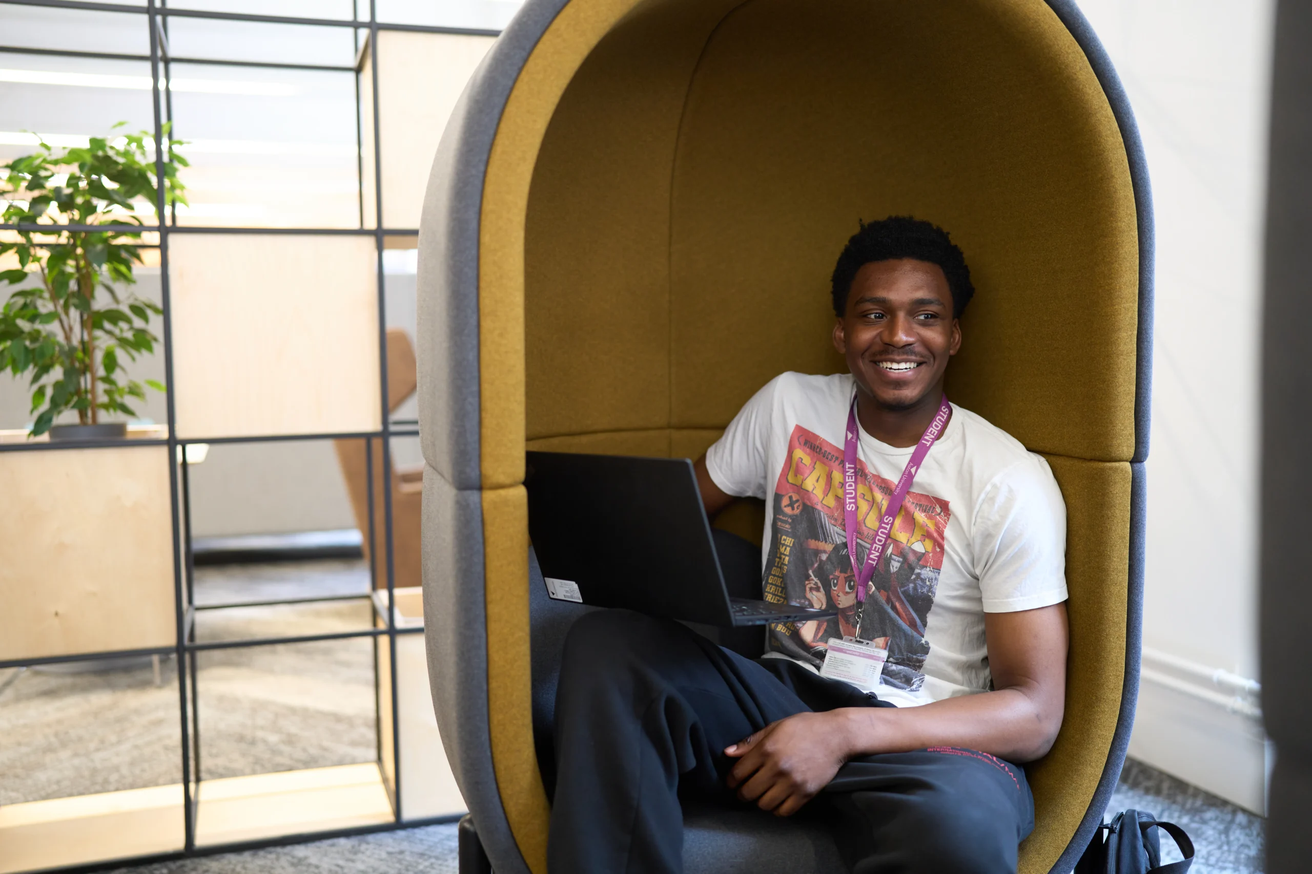 Aston University ranks amongst the Best in the World for Business and Marketing in the 2025 QS World Rankings - smiling man on laptop in pod chair