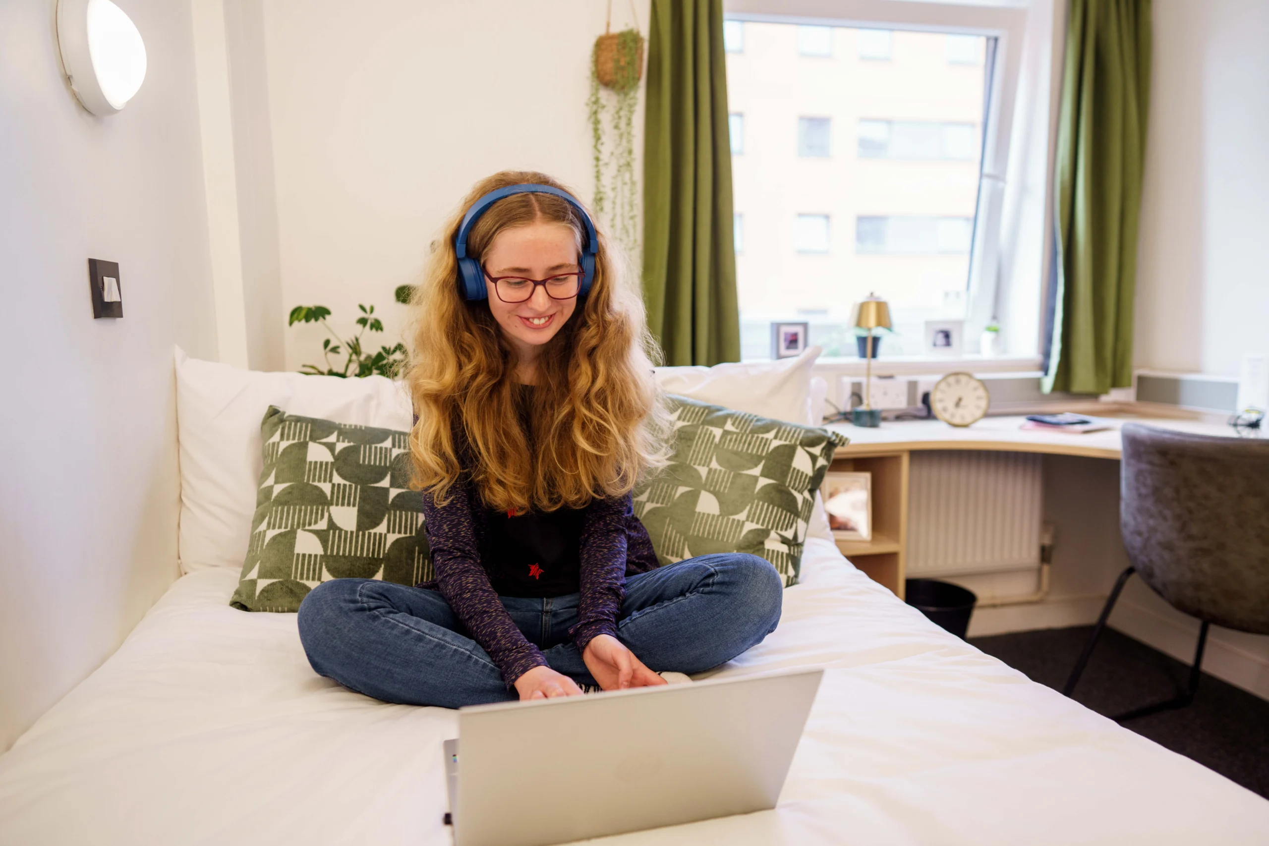 Early deposit payment - woman wearning headphones sits on bed with laptop