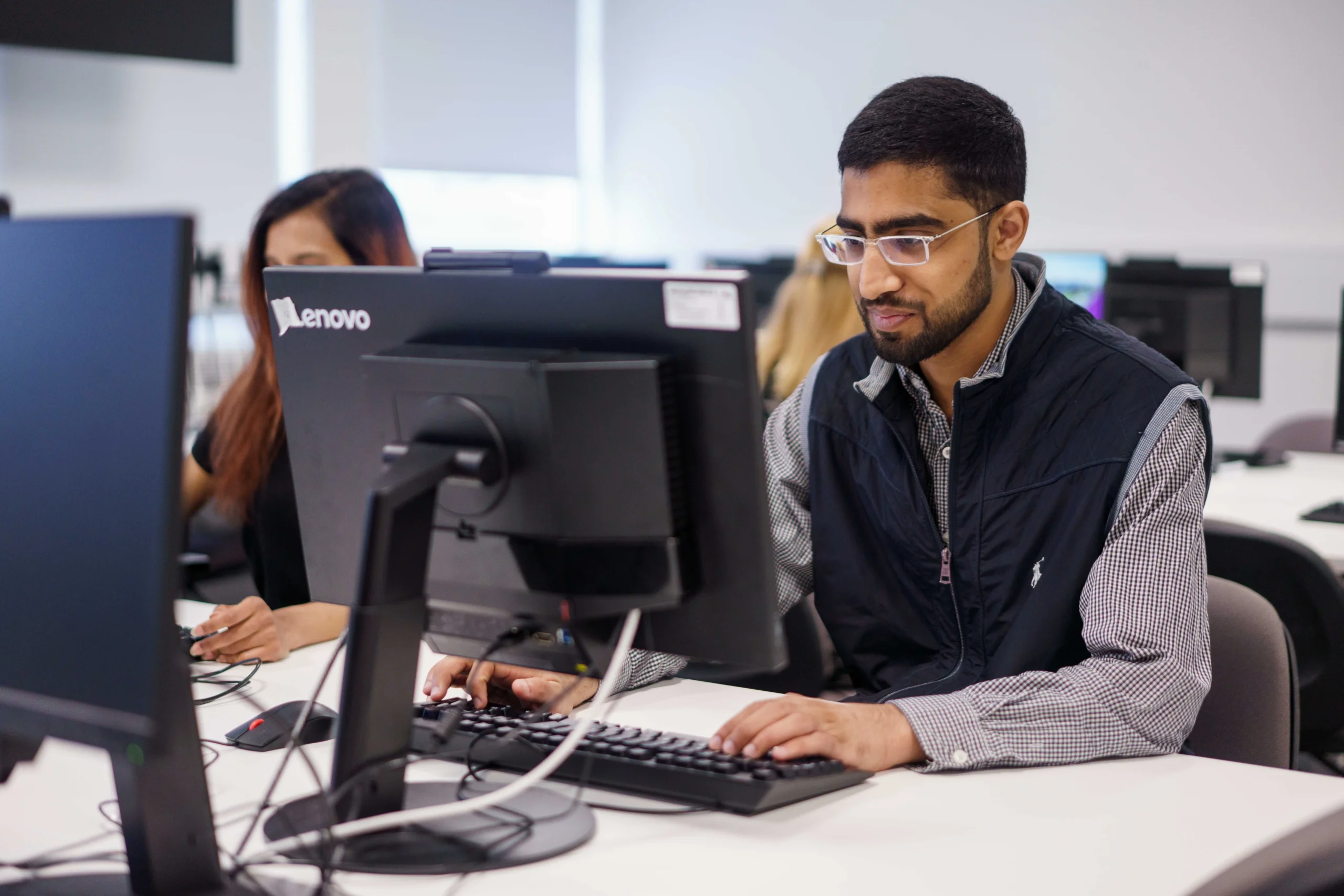 How Aston’s Business Analytics programme prepares you for predictive decision-making - man with glasses in front of computer screen typing on keyboard