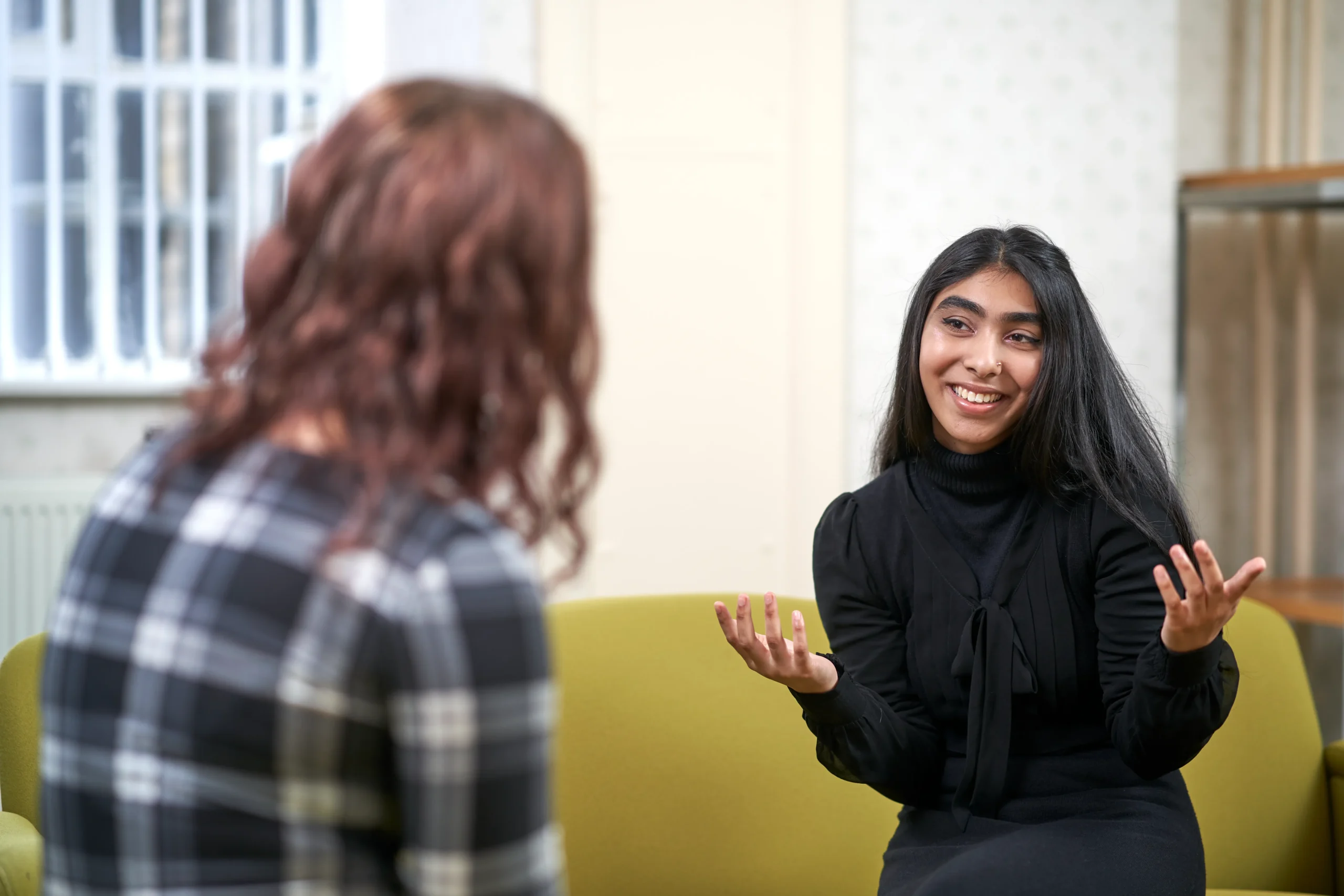 How to become a psychological wellbeing practitioner in the UK - woman speaking to another woman on chartreuse couch