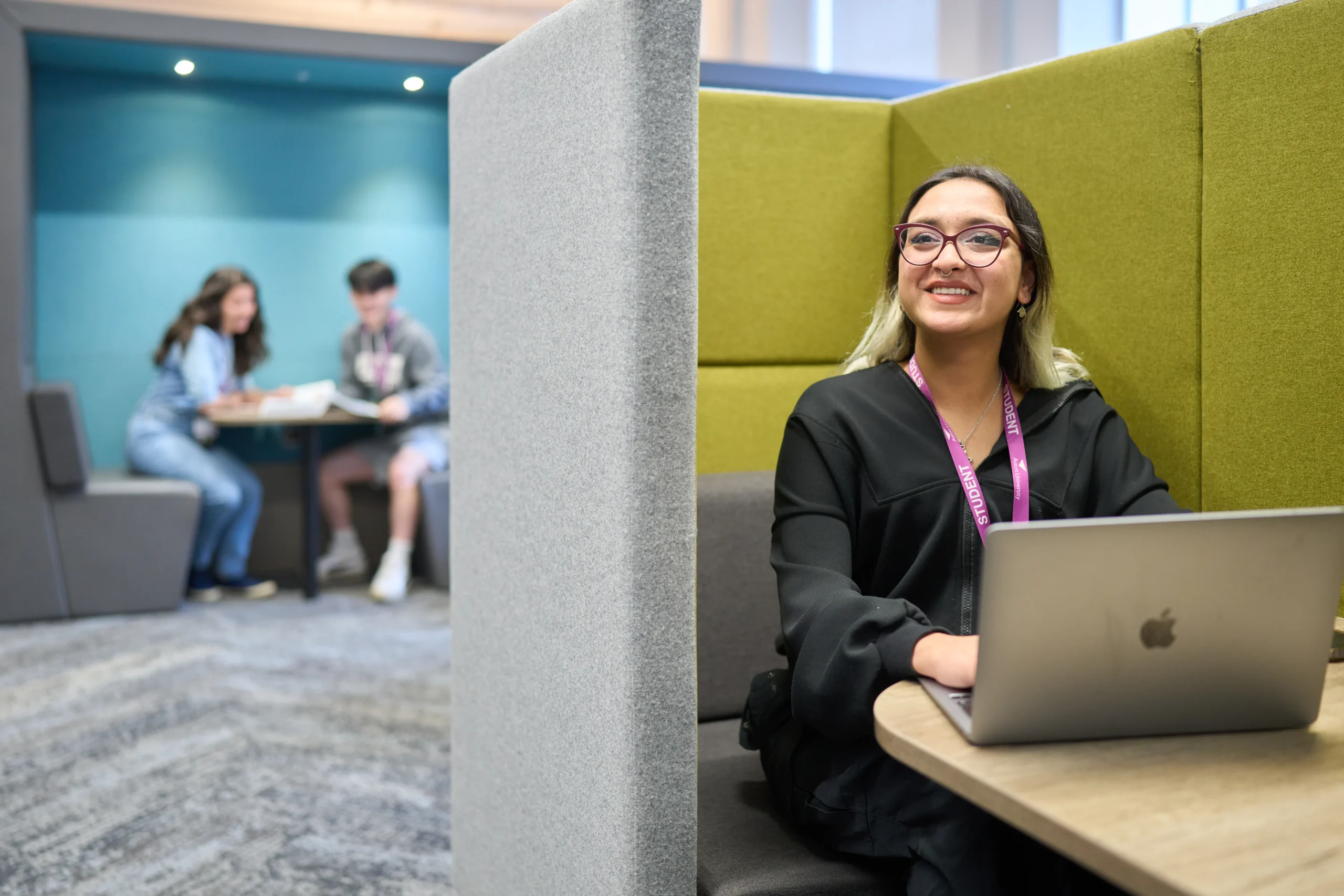 The key qualities for success in an online MBA at Aston University - smiling woman in office pod with laptop