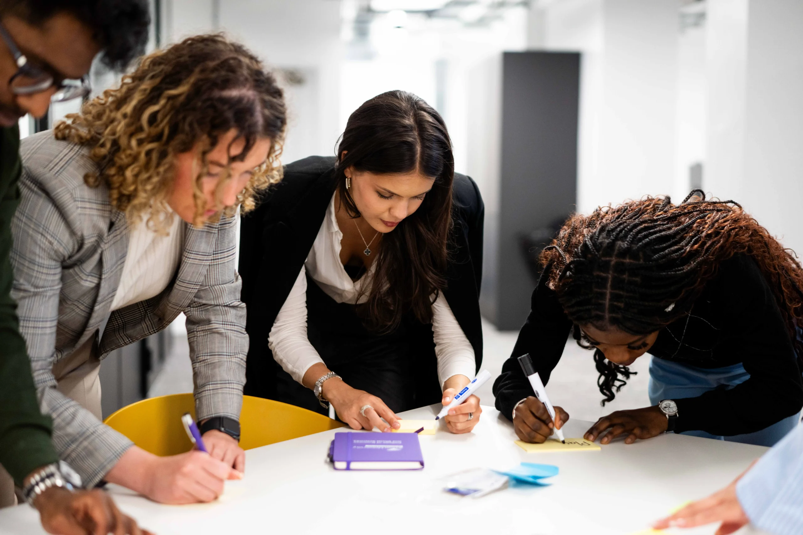 Triple Crown accreditation awarded to Aston Business School - Business students leaning over desk writing notes