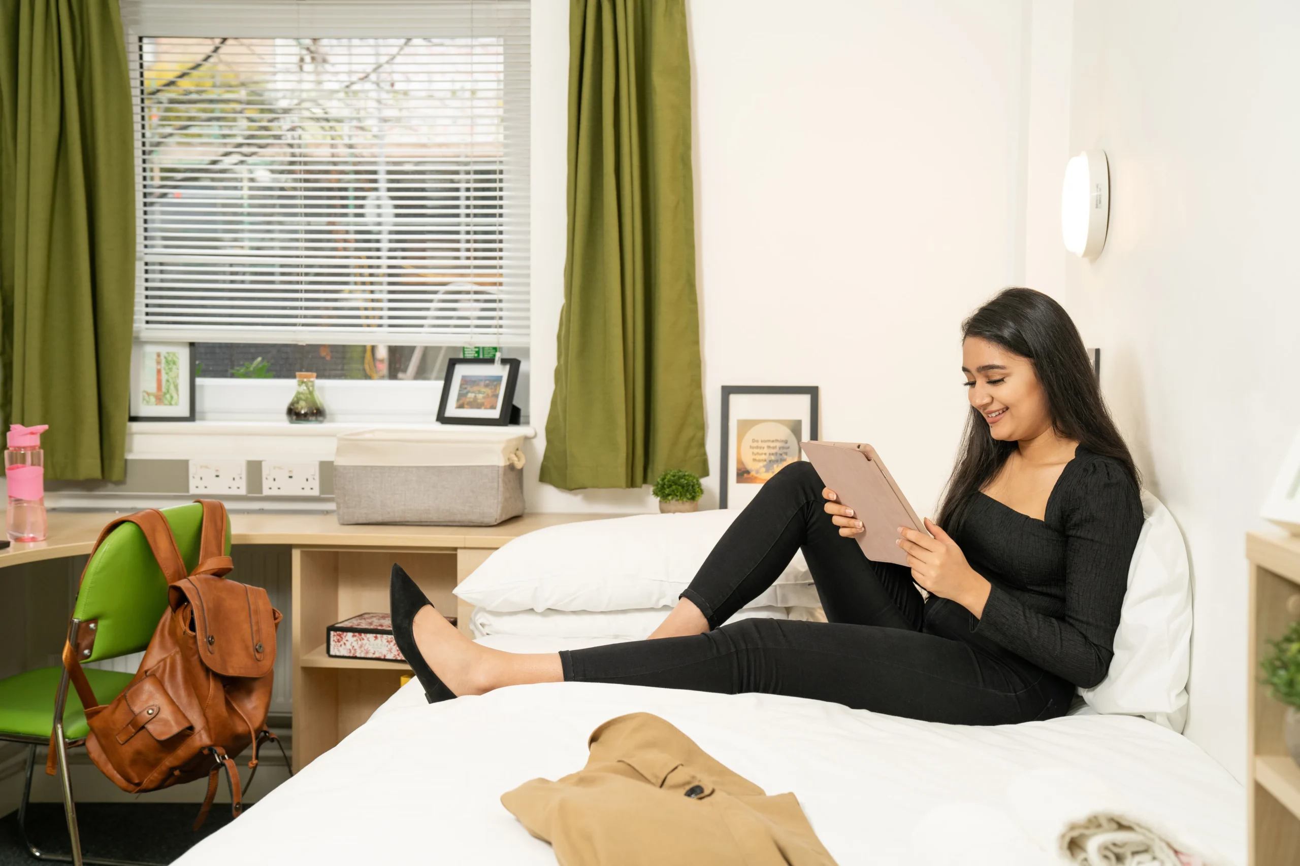 Aston Online - How flexible UK online study prepares you for remote work - woman sitting on bed, smiling at screen