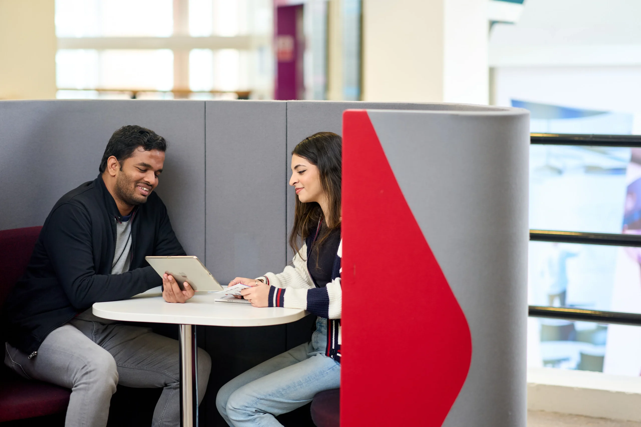 What can you do with a Master of Science in Business Analytics - two students in a grey and red pod talking and sharing a tablet