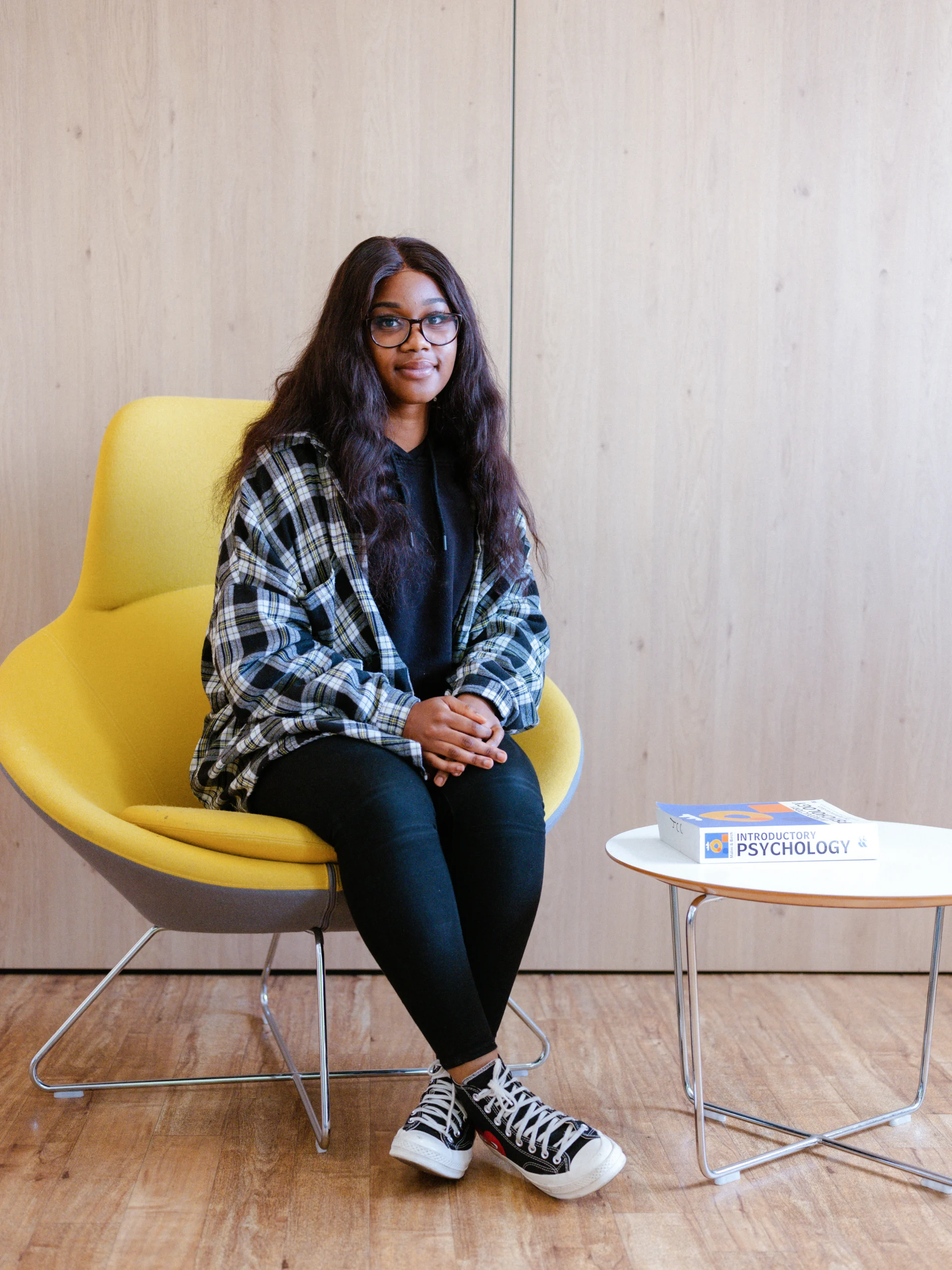 Do you need Psychology GCSE or A-Level to study psychology in the UK feature blog - Psychology student sitting in chair with a psychology textbook next to her