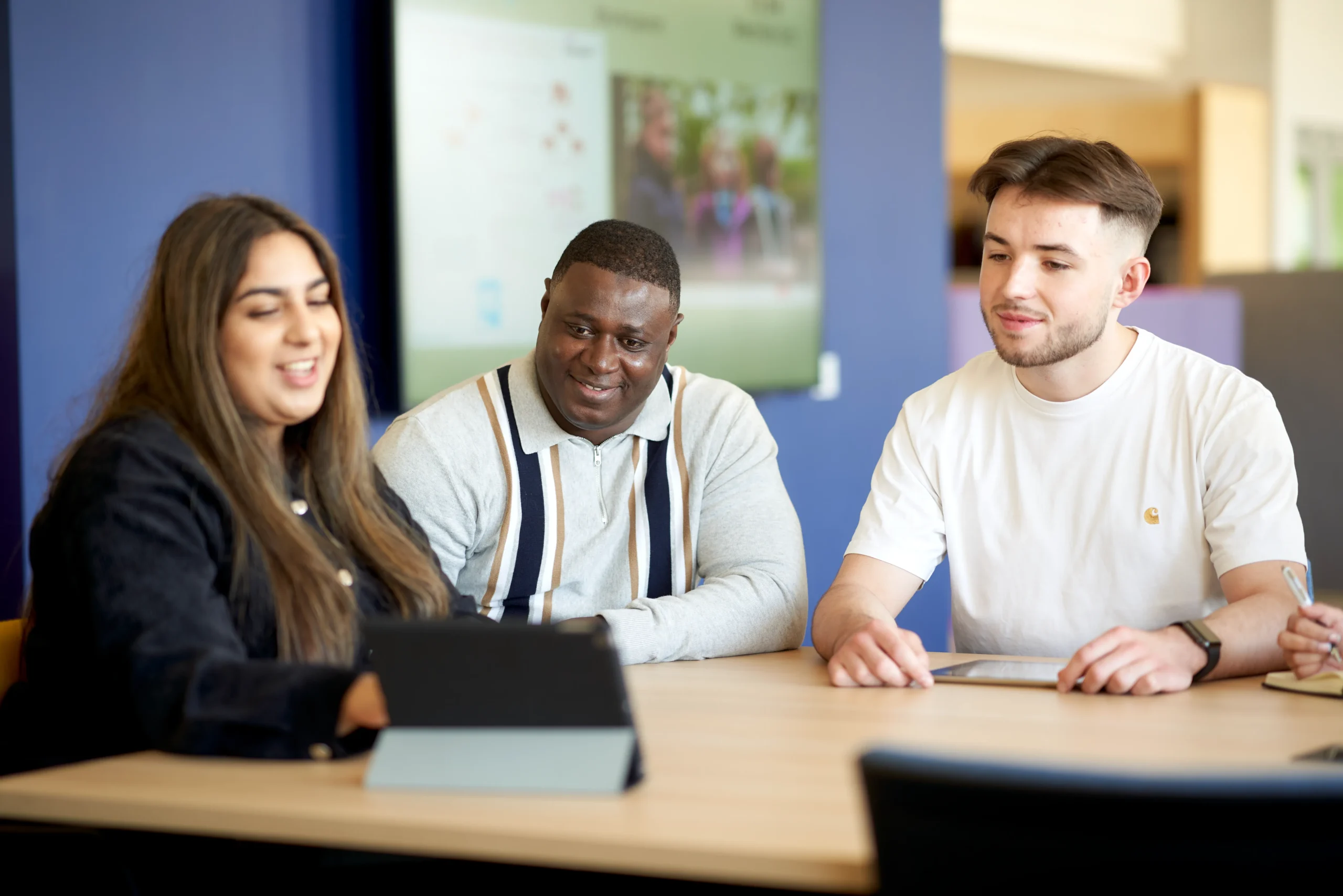 Enhancing career growth: Aston Online MBA for working professionals - group of students gathered around an ipad at a table