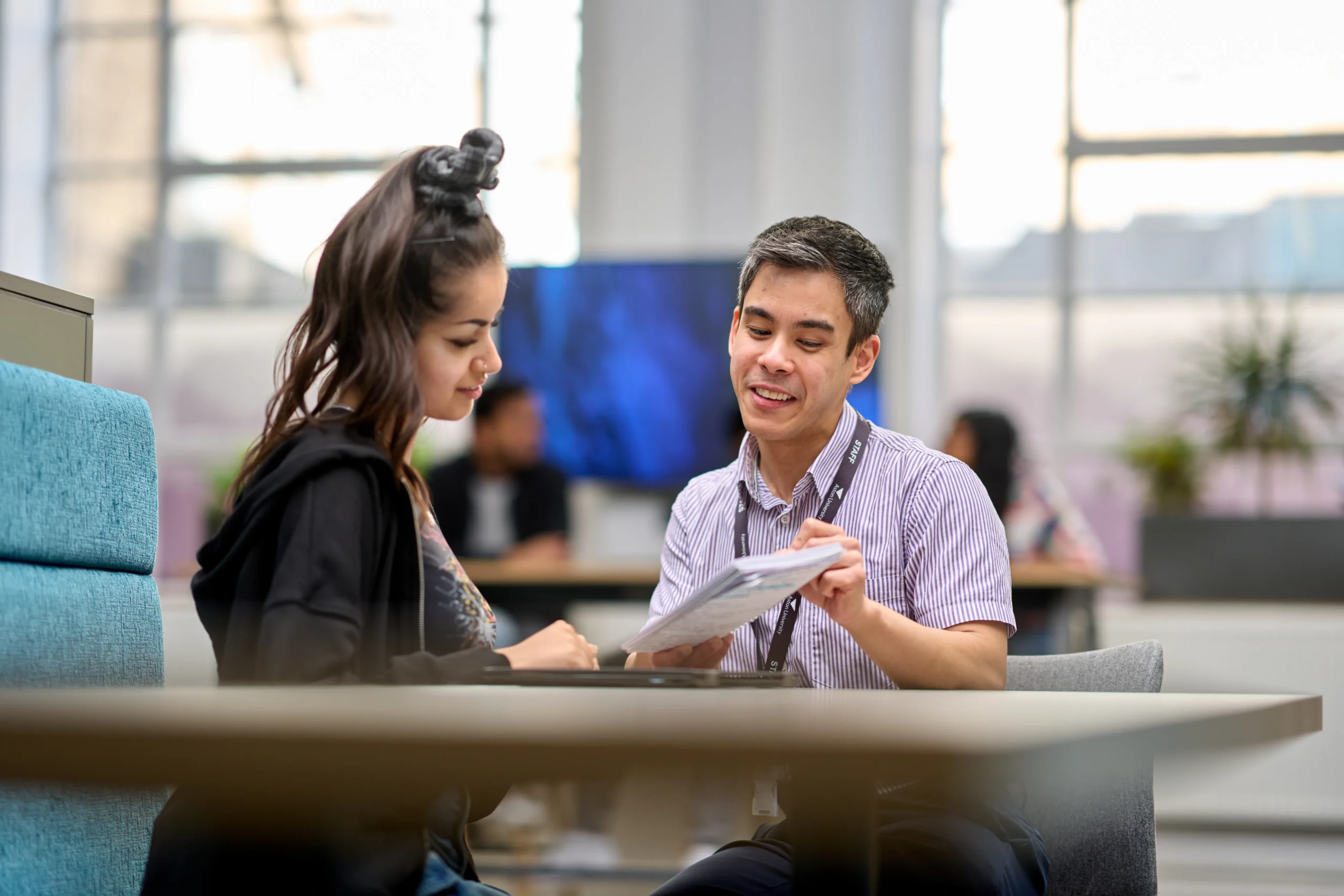 How DBA and PhD students in business differ - Man explaining notes to a young woman student at a table
