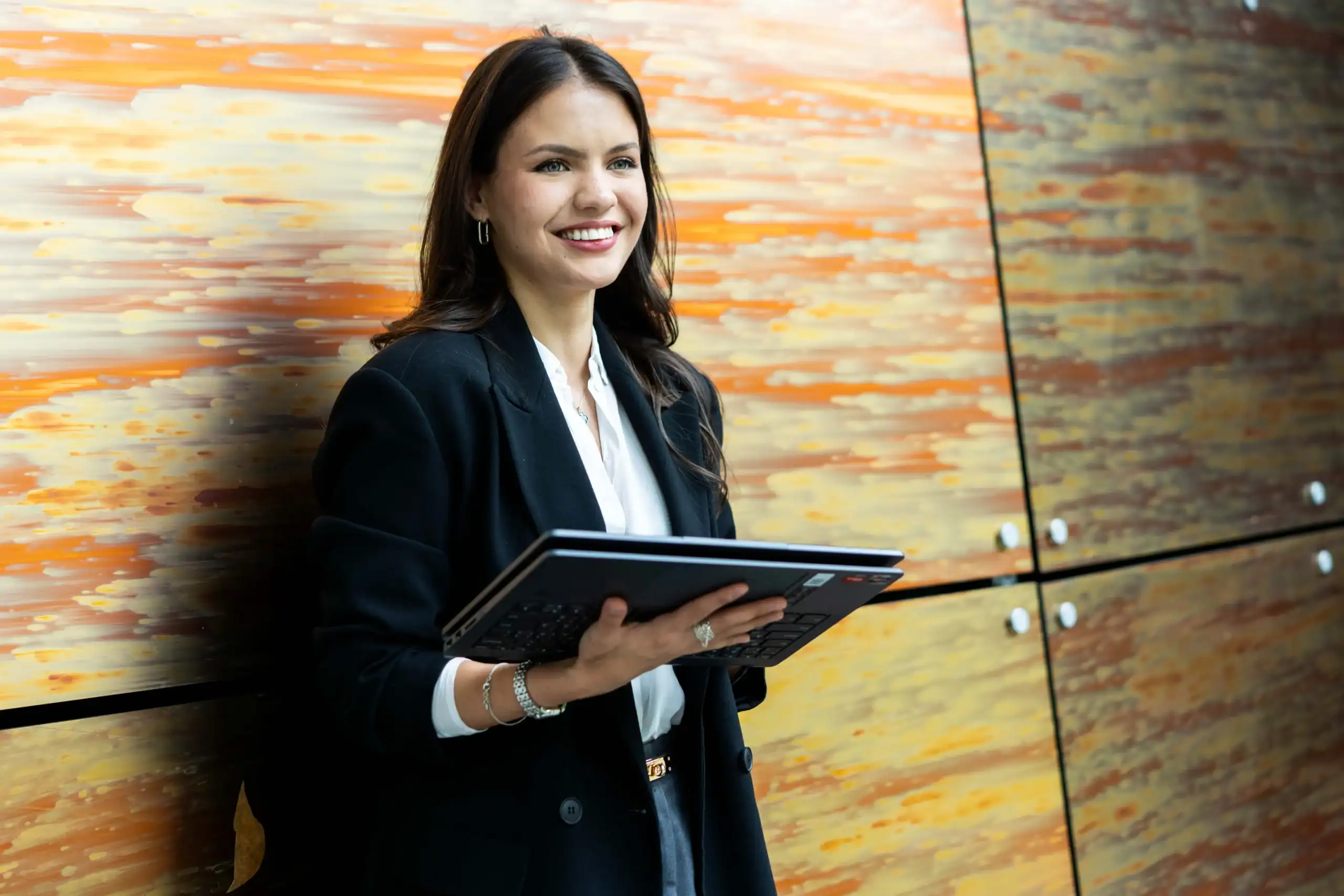 Our MSc Business Analytics achieves IoA Accreditation - woman holding partially closed laptop in front of orange wall