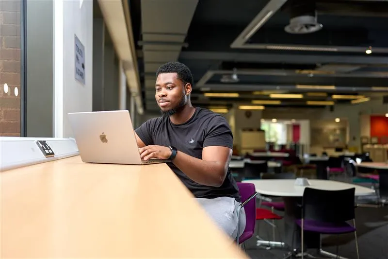 Our computer science degrees are now BCS-accredited - man working in co-working space with laptop at counter desk