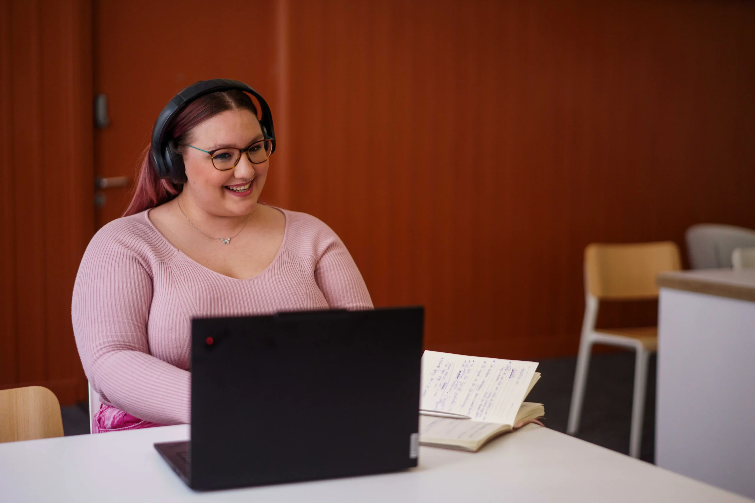Shape public health systems with an online Master of Public Health - woman in pink jersey in online meeting with headphones in front of laptop