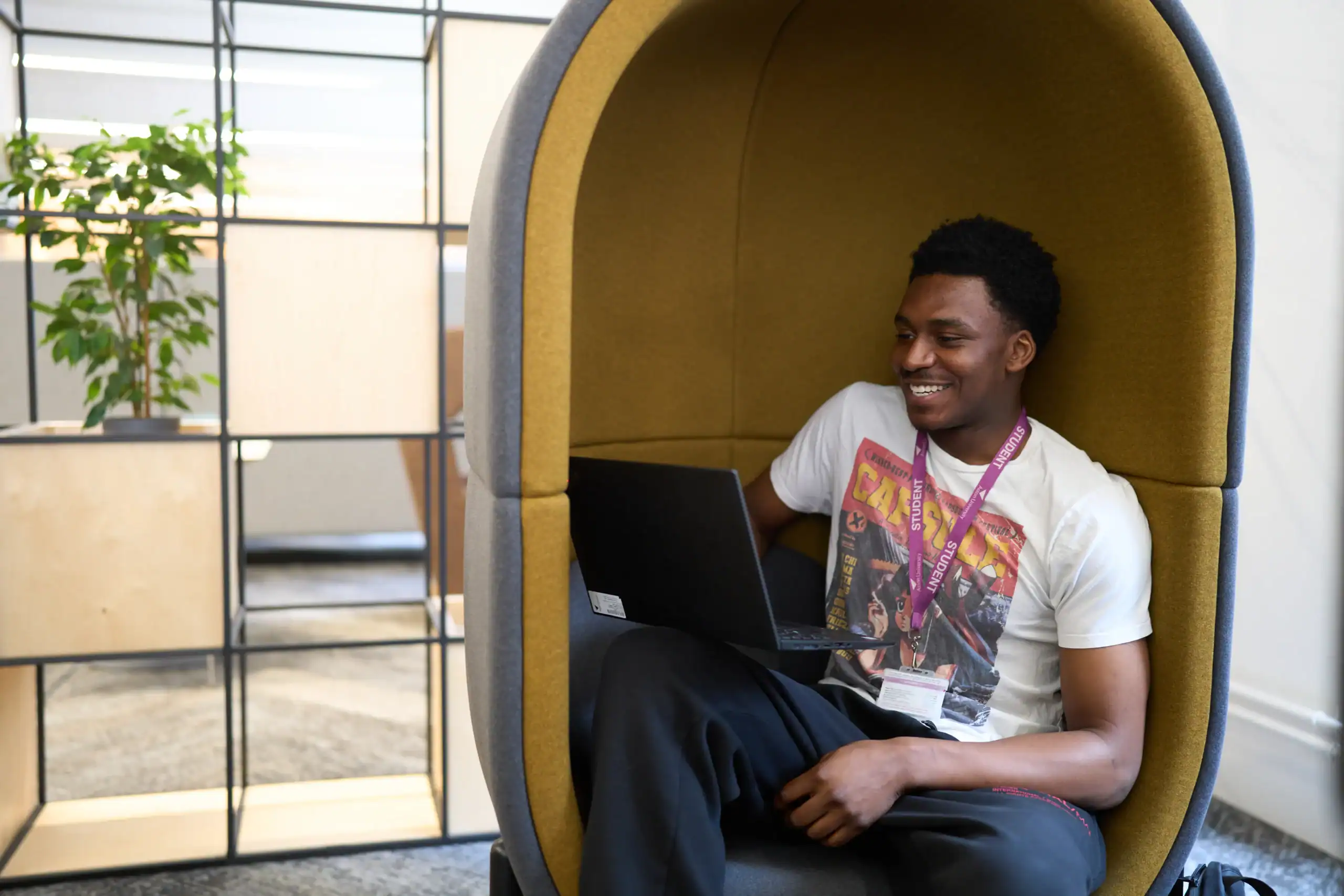 Student support advisors - man sits in booth chair with laptop speaking to student advisor virtually