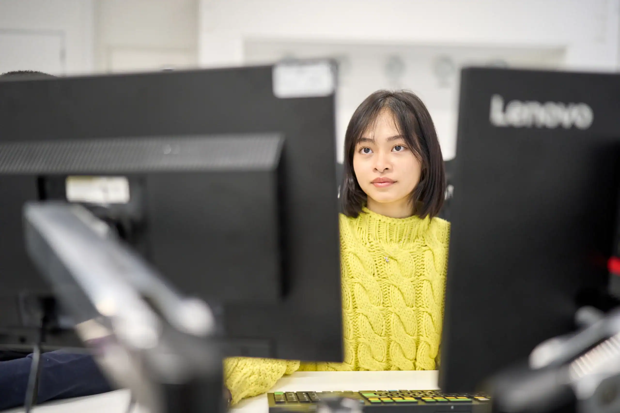 The difference between software developers and software engineers - woman looking at two screens in an office