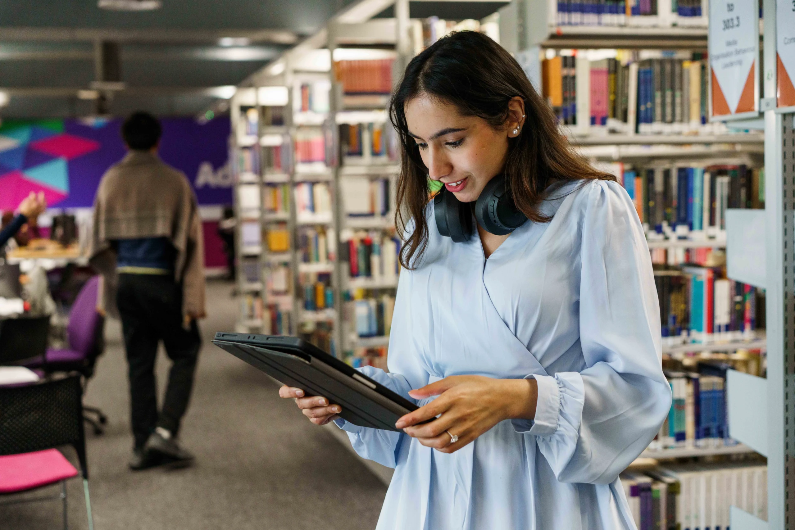 Time management strategies for busy online students - woman in library looking down at tablet
