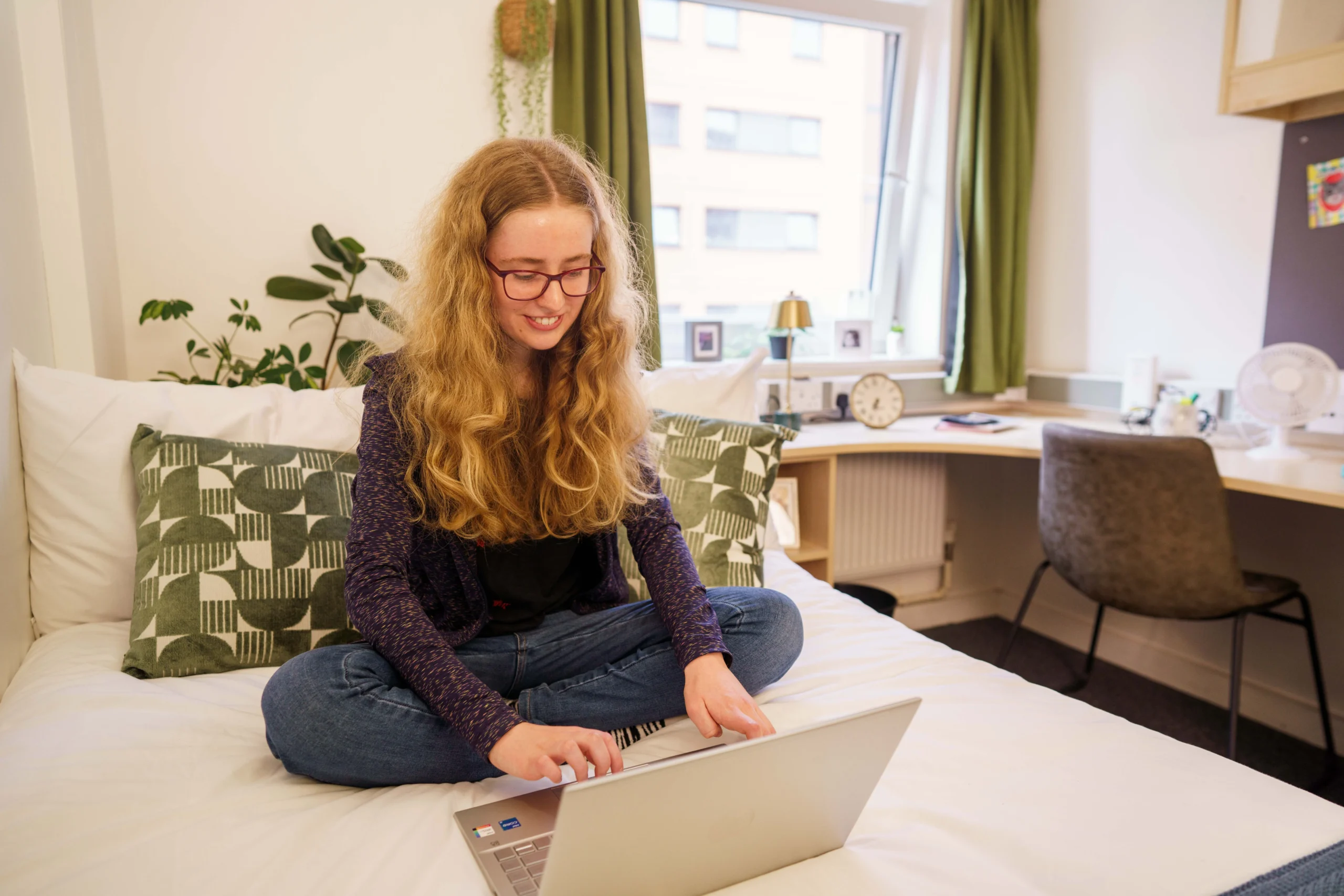 Your guide to navigating the Aston Online Digital Campus - woman sitting cross-legged working on laptop on bed