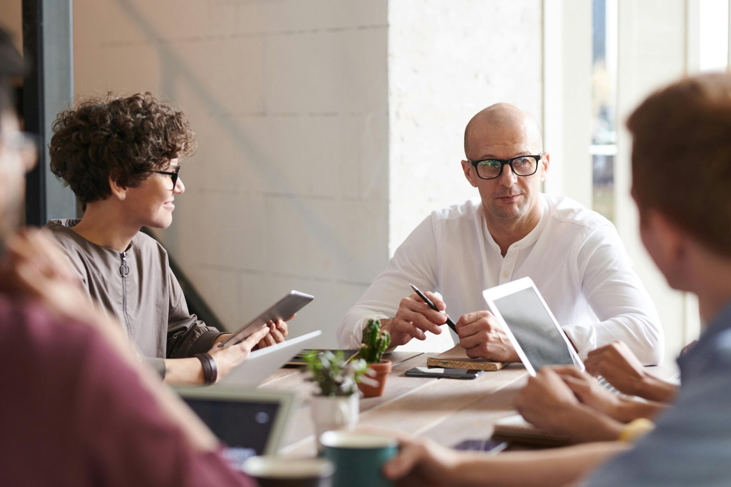 Exploring career prospects and in-demand skills for graduates with a BSc in Business and Management - team meeting with man leading at head of table with people on devices